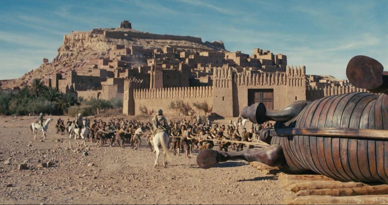 A production still from "The Odyssey" shows a large wooden horse structure in front of a fortified settlement. (Photo via IMDb)