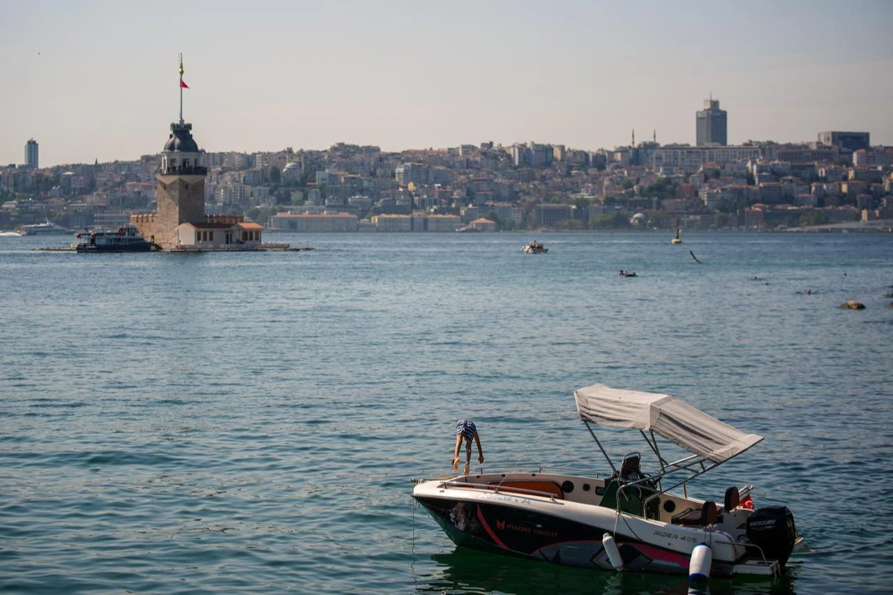 A citizen, overwhelmed by the hot weather and humidity, jumps into the sea in front of the Maiden's Tower to cool off at Salacak beach in Istanbul, Türkiye, July 22, 2026. (AA Photo)