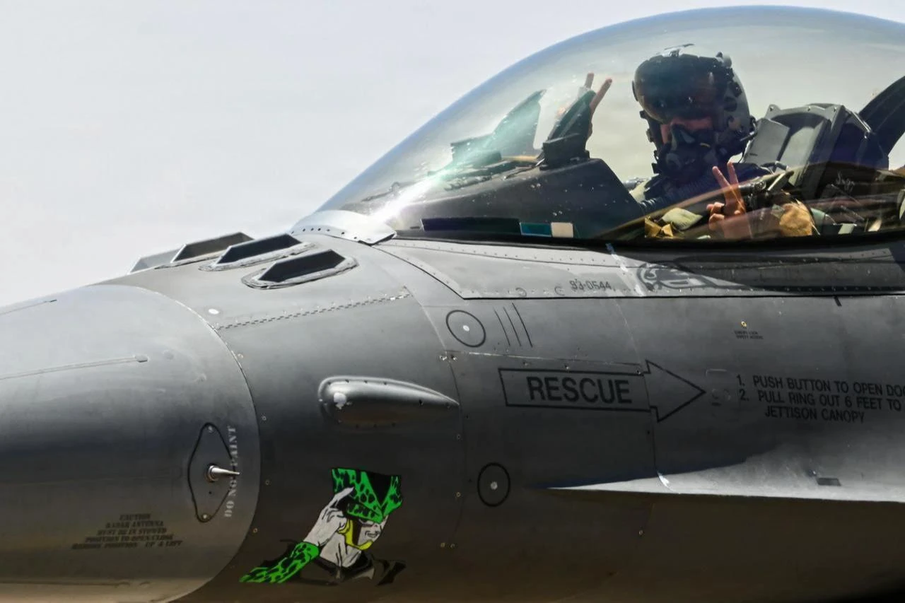 A U.S. Air Force pilot throws a squadron hand signal while taxiing a U.S. F-16 Fighting Falcon aircraft at a base in the U.S. Central Command area of responsibility June 18, 2026. (Photo via U.S. Air Force)
