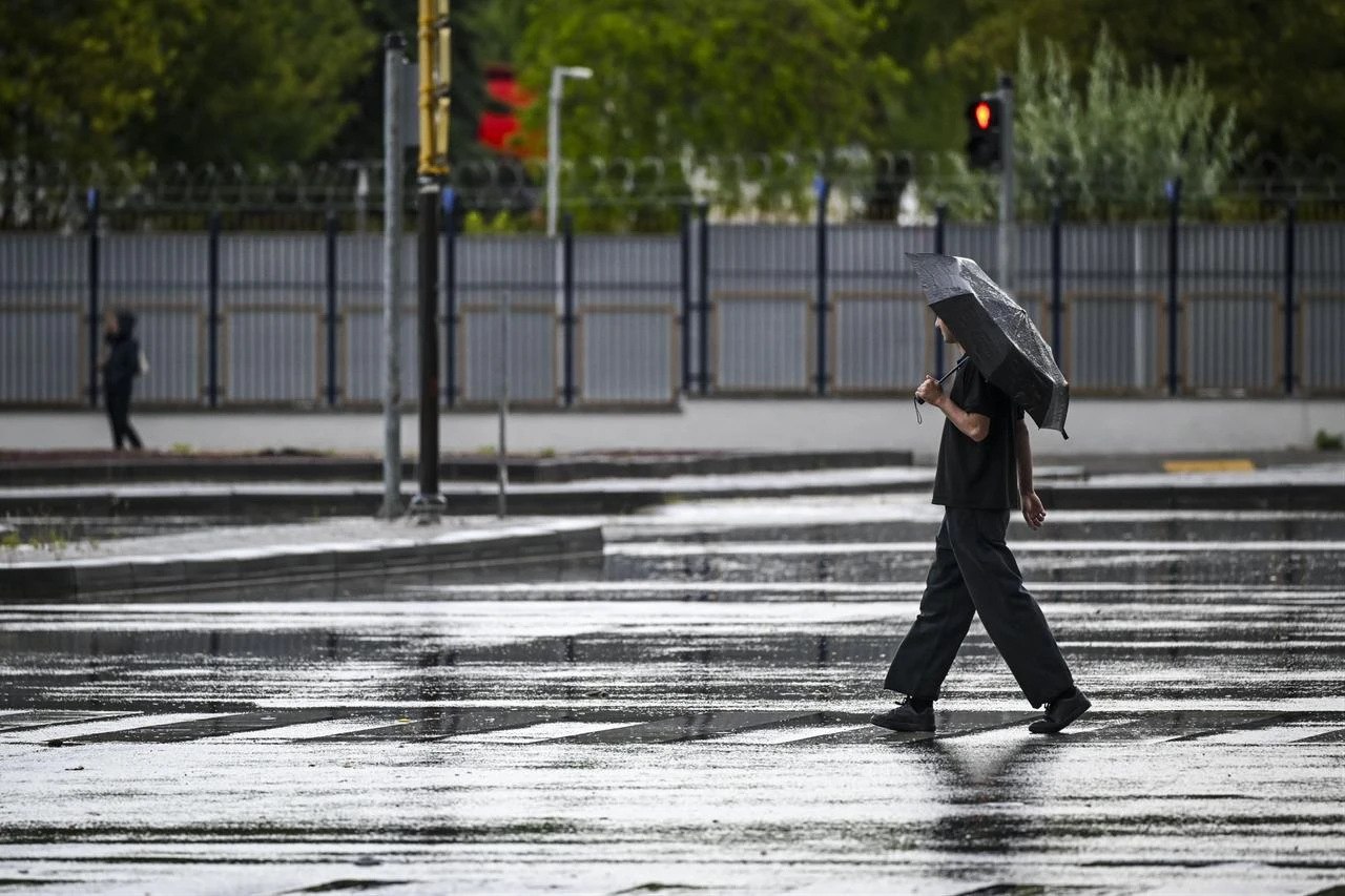 A pedestrian carrying an umbrella crosses a street during heavy rainfall in Ankara, Türkiye, on July 25, 2026. (AA Photo)