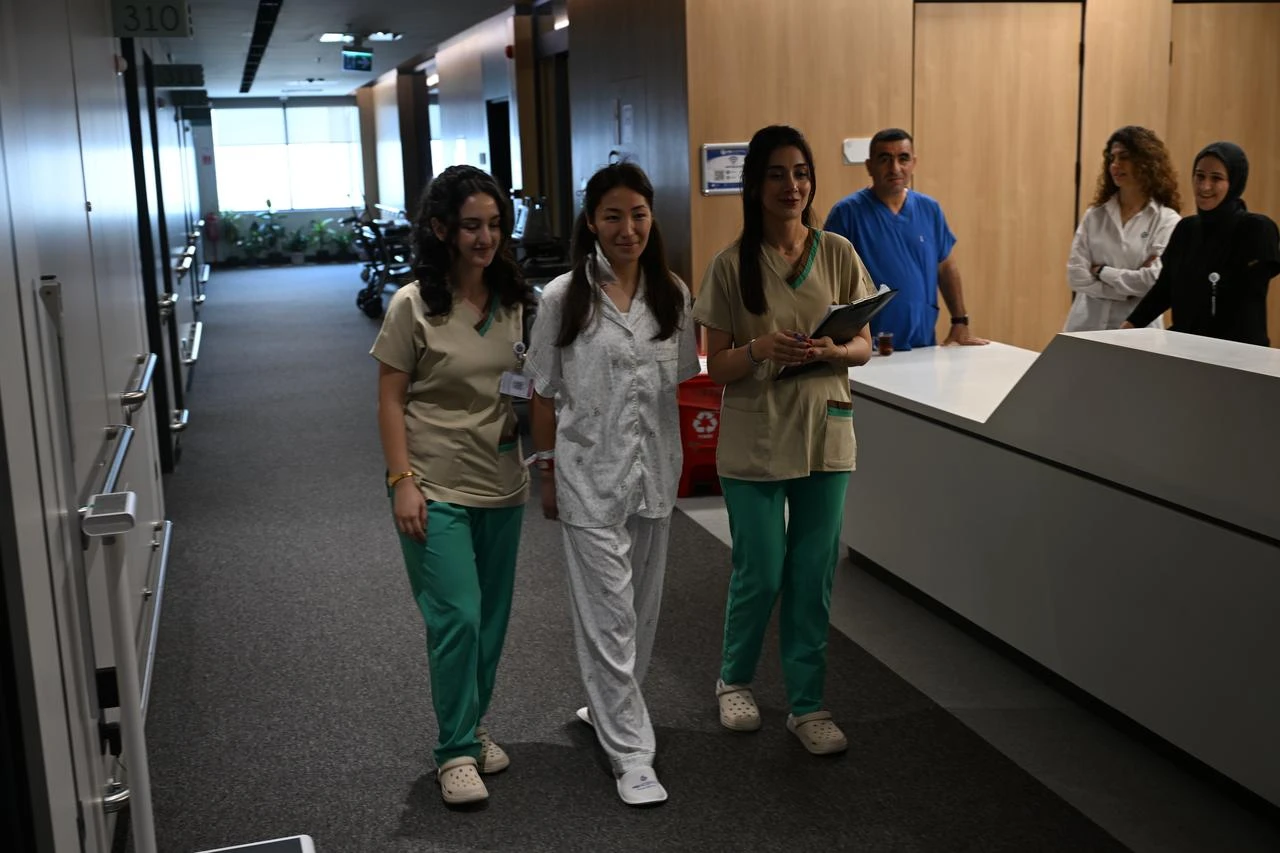 Zarina Narynbek walks through a hospital corridor with medical staff after receiving treatment for pheochromocytoma in Türkiye, July 26, 2026. (AA Photo)