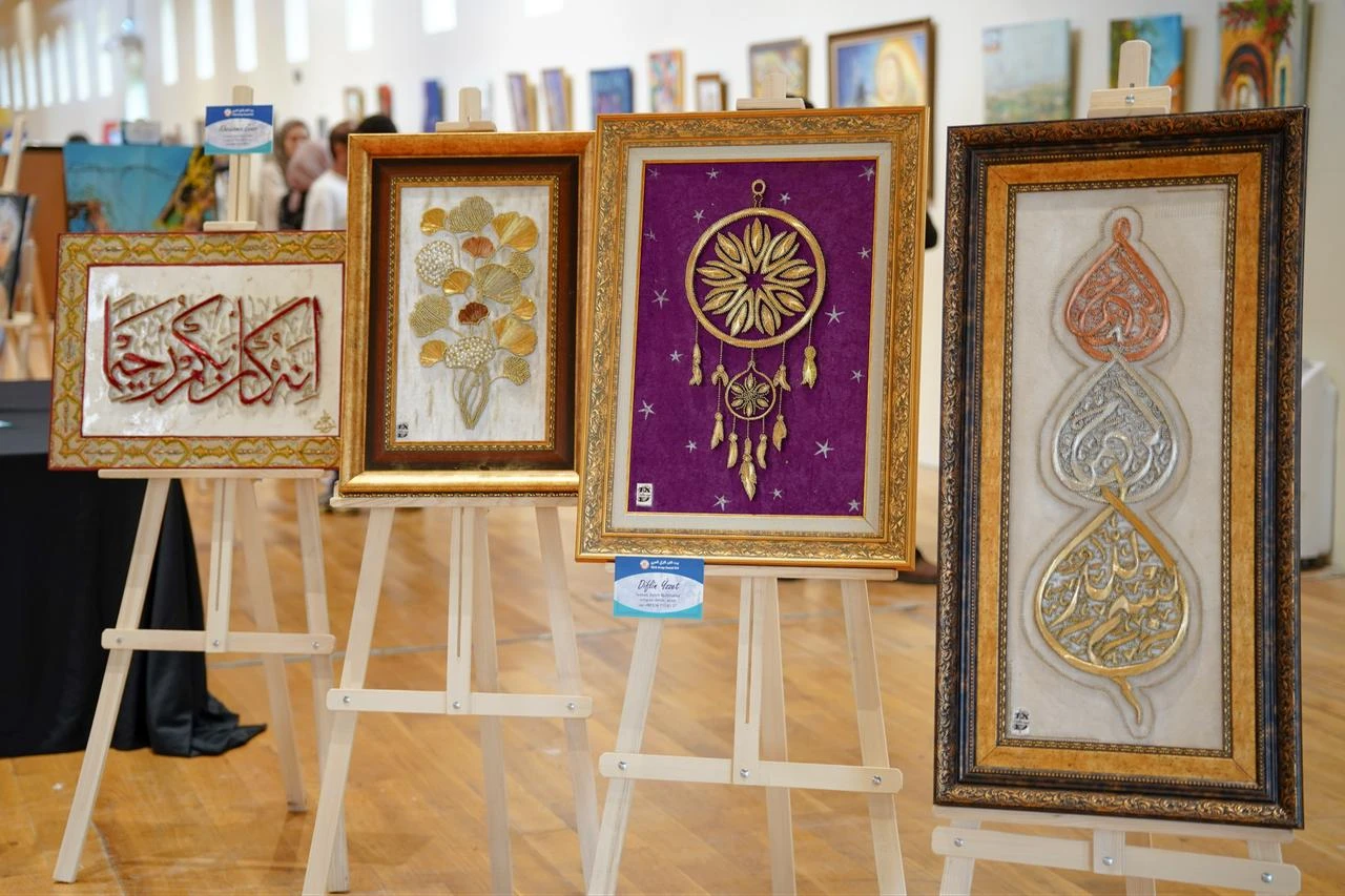 Framed calligraphy and textile artworks are displayed during the 8th Turkish-Arab Artists Meeting at Rami Library in Istanbul, Türkiye, July 25, 2026. (AA Photo)