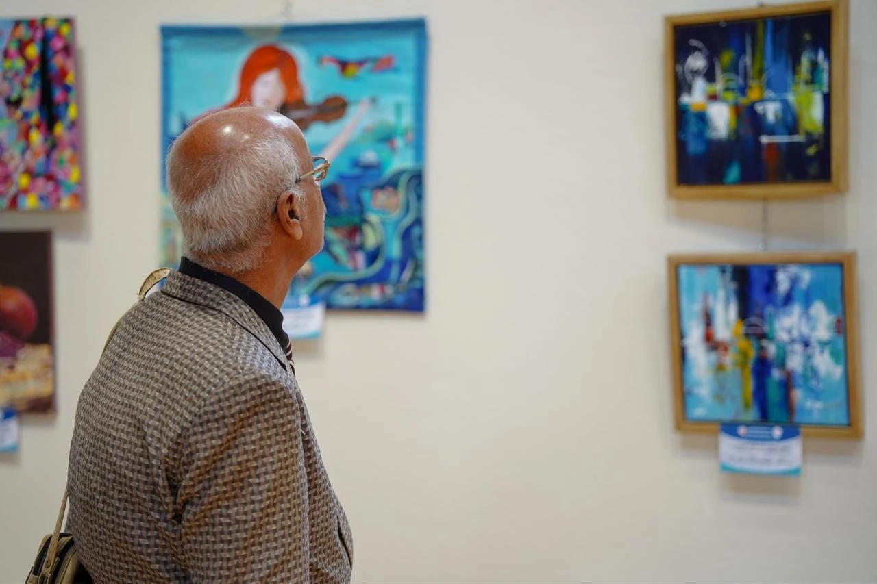 A visitor examines paintings during the 8th Turkish-Arab Artists Meeting at Rami Library in Istanbul, Türkiye, July 25, 2026. (AA Photo)