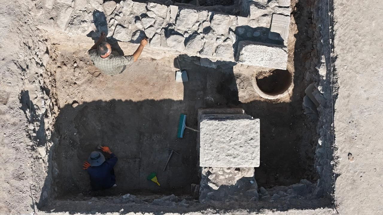 An overhead view shows archaeologists working beside an ancient storage jar in the Western Bath area of the Apollo Smintheus Sanctuary in Canakkale, Türkiye, July 2026. (IHA Photo)