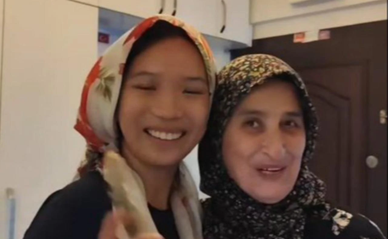A Chinese traveler smiles alongside her Turkish host after receiving a traditional patterned headscarf during a visit to a family home in Ankara, Türkiye. (Photo via Türkiye Daily)