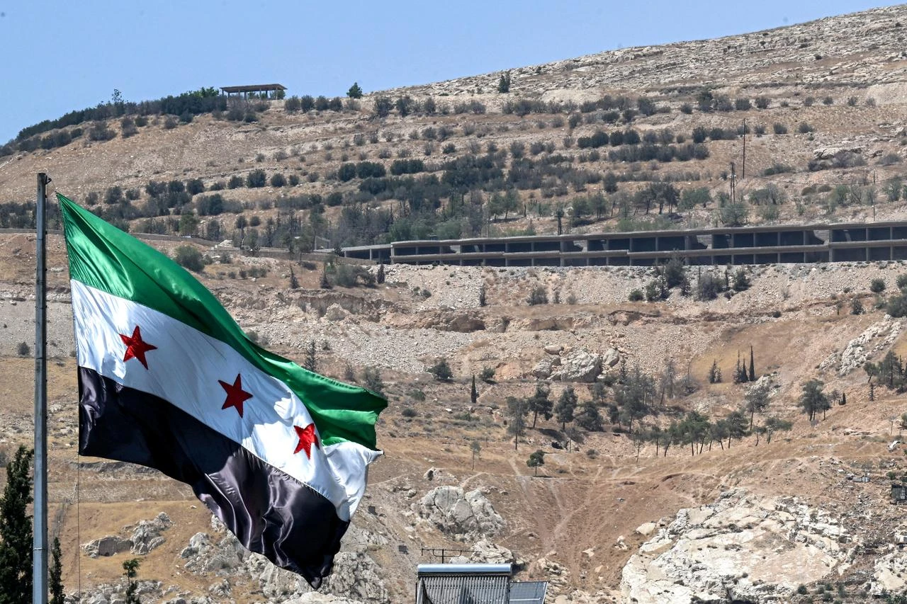 The Syrian flag flies at the Umayyad Square in Damascus on July 22, 2026, with Mount Qasioun pictured in the background. (AFP Photo)