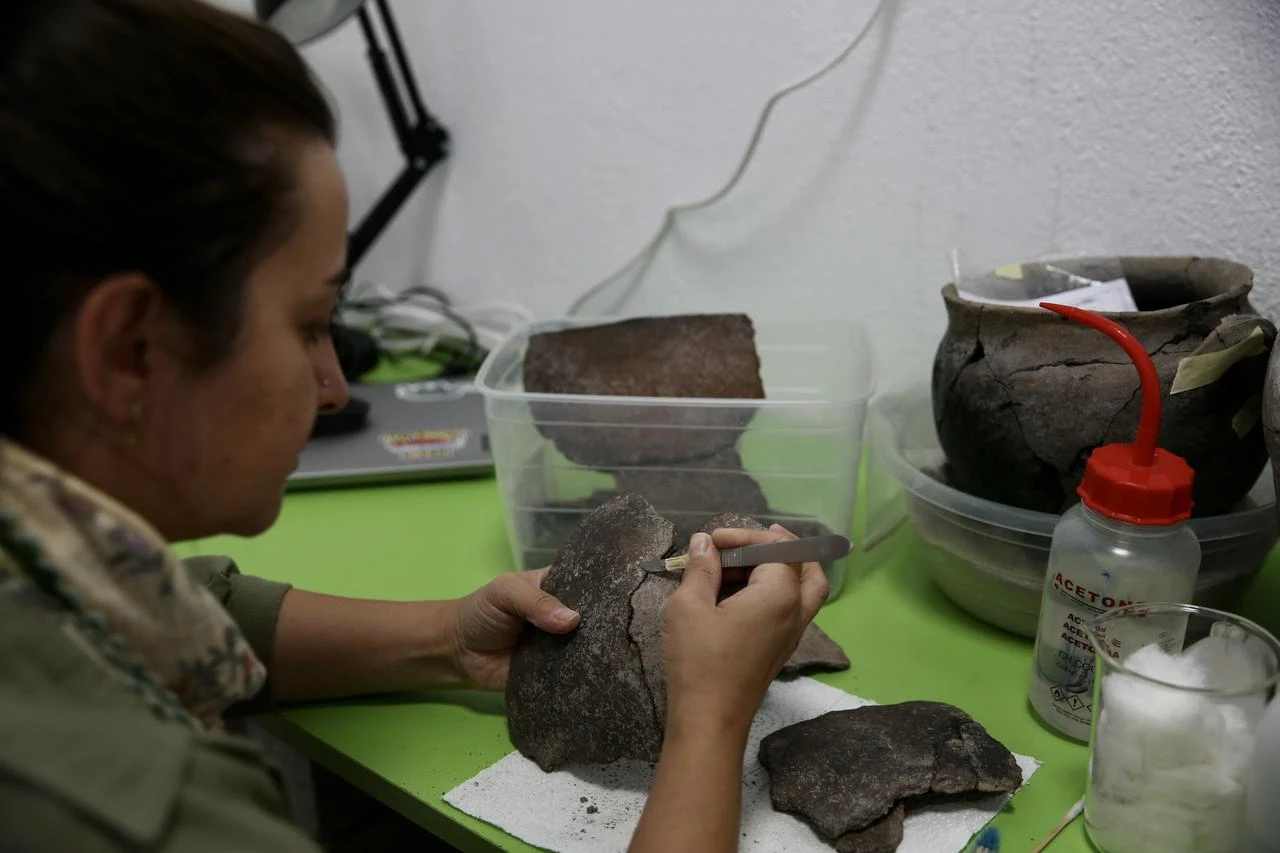 A member of the excavation team cleans and examines pottery fragments recovered from Caltilar Hoyuk. (AA Photo)