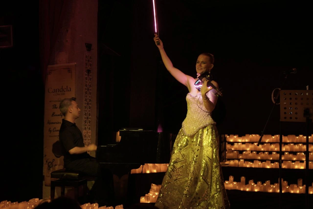 Candela Concert raises an illuminated bow as a pianist accompanies her during the Candela Concert at Beyoğlu Sahne in Istanbul, Türkiye, July 26, 2026. (AA Photo)