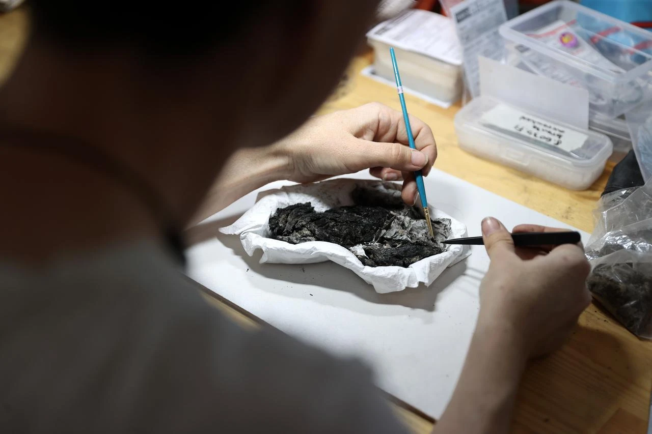 A specialist carefully cleans and examines material uncovered during excavations at Turkmen Karahoyuk. (AA Photo)