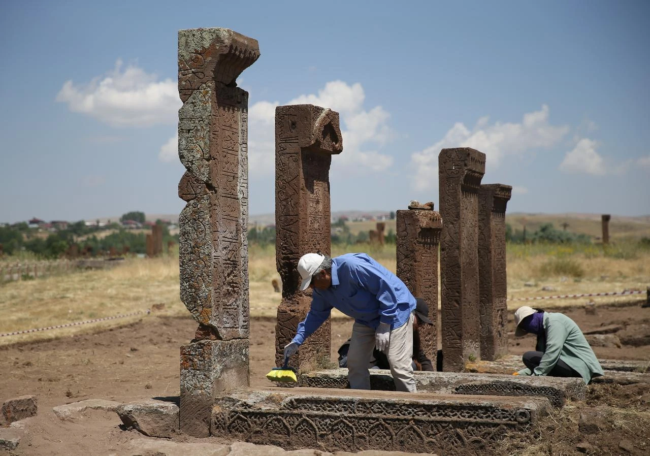 Researchers work among newly uncovered graves and inscribed tombstones at the Seljuk Square Cemetery in Ahlat, Bitlis, Türkiye, July 28, 2026. (AA Photo)