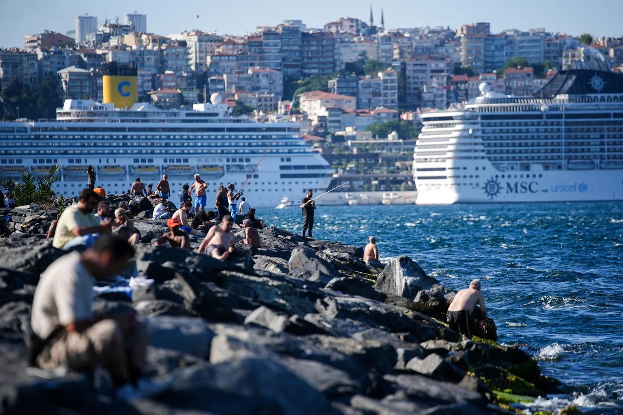 People gather along the shoreline as cruise ships pass through the Bosporus during hot weather in Istanbul, Türkiye, July 19, 2026. (AA Photo)