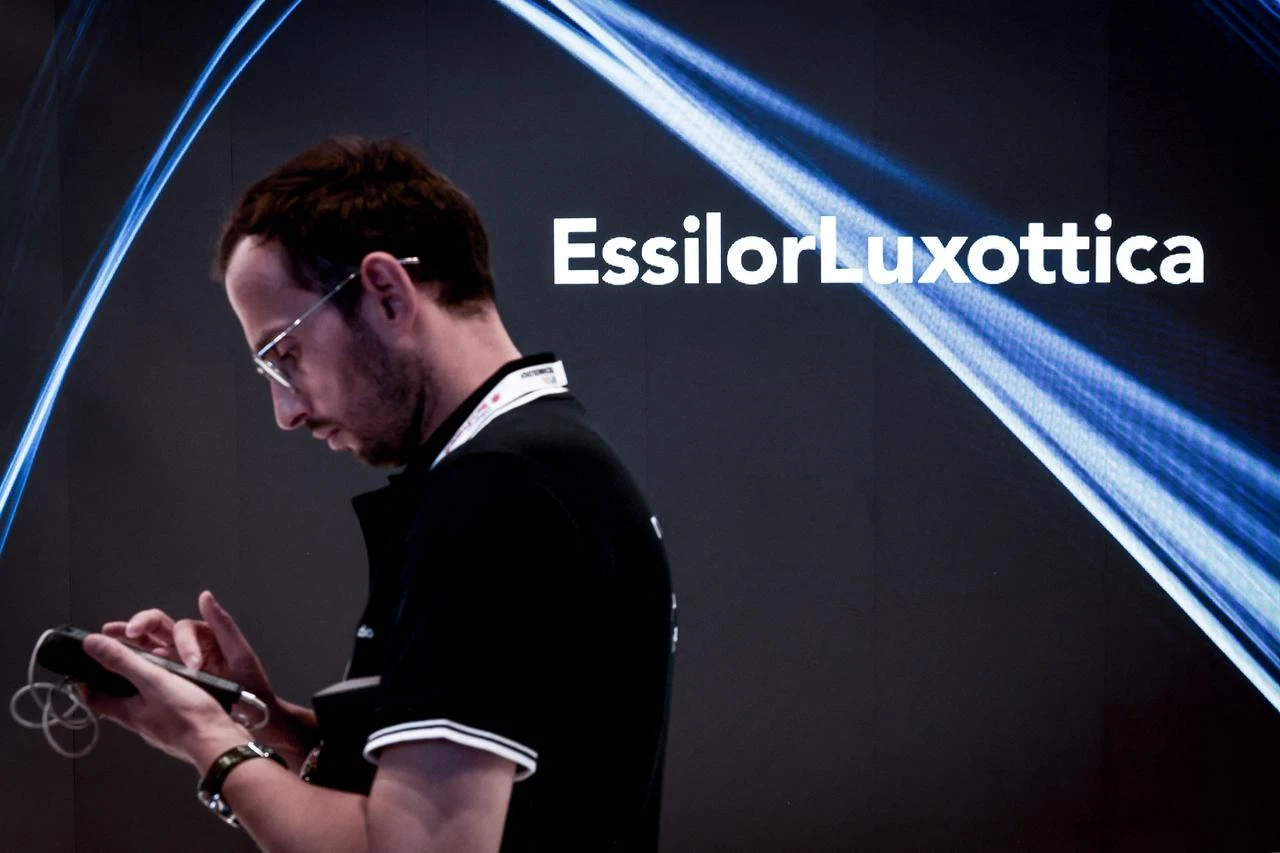 Man examines his mobile telephone as he passes by the EssilorLuxottica logo at the Paris Expo Porte de Versailles, in Paris on June 11, 2025. (AFP Photo)