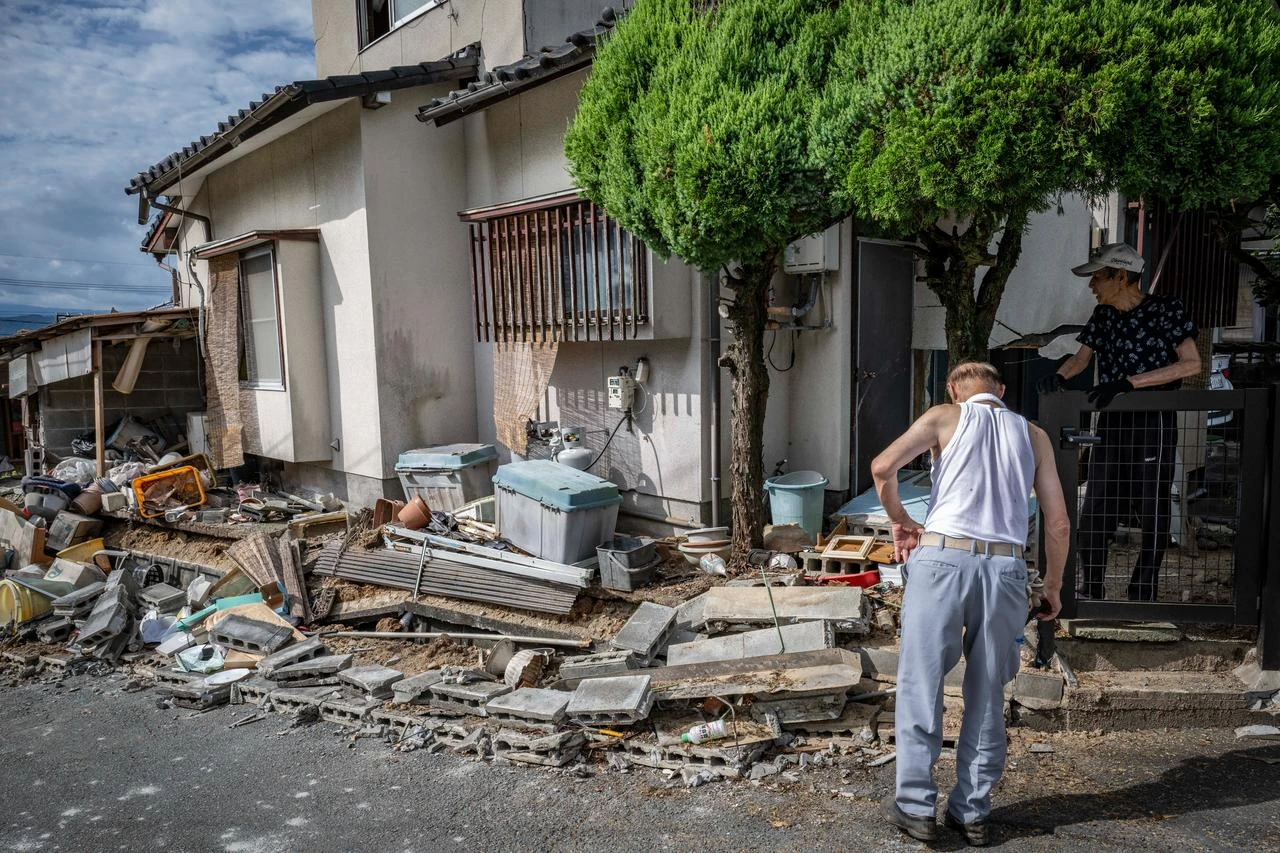 Neighbors talking beside a collapsed concrete block wall of a damaged house by the 7.1-magnitude earthquake in Uki city, Kumamoto Prefecture, on July 29, 2026. (AFP Photo)