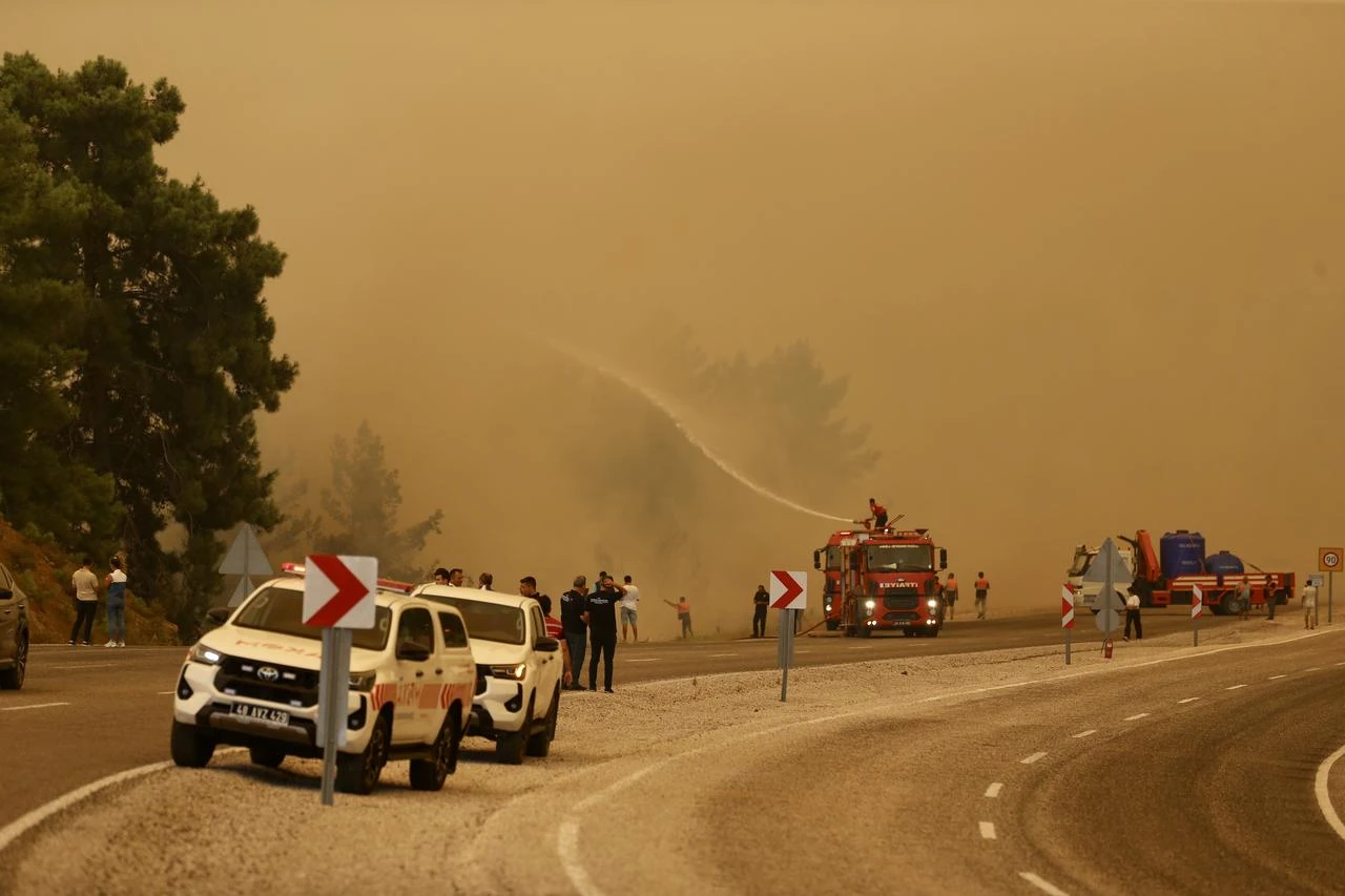 Fire crews and emergency vehicles operate along the Fethiye-Antalya highway as thick smoke from a forest fire reduces visibility in the Seydikemer district of Mugla, on July 29, 2026 in Mugla, Türkiye. (AA Photo)