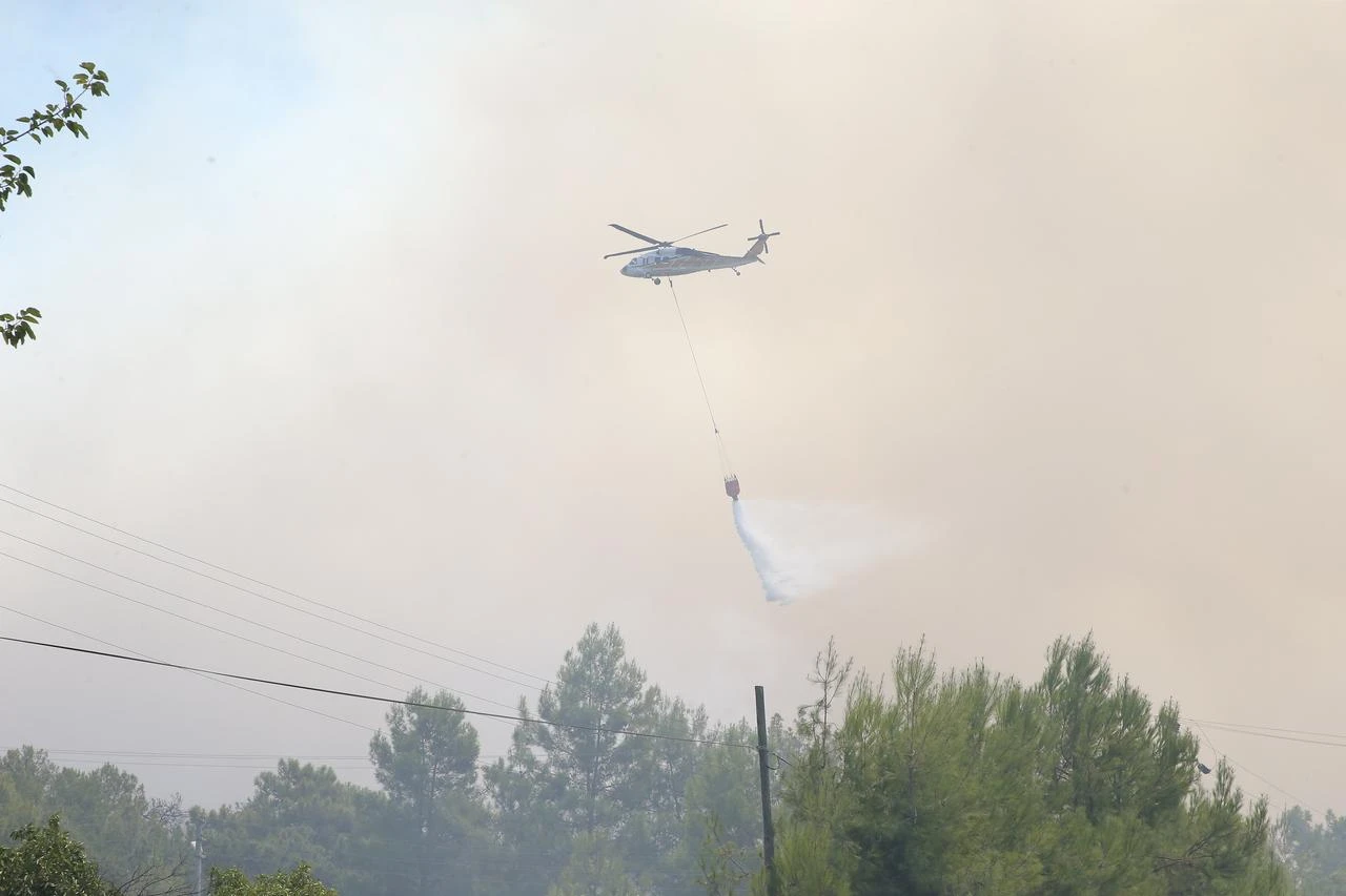 A firefighting helicopter drops water over wildfire in Fethiye, Mugla, Türkiye, July 29, 2026. (AA Photo)