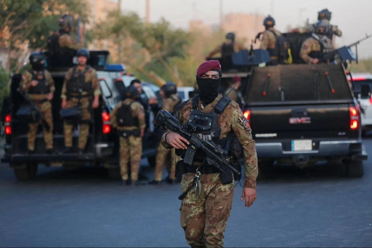 Members of the Popular Mobilization Forces lift flags as they line up during a funeral procession in Baghdad on June 22, 2025. (AFP Photo)