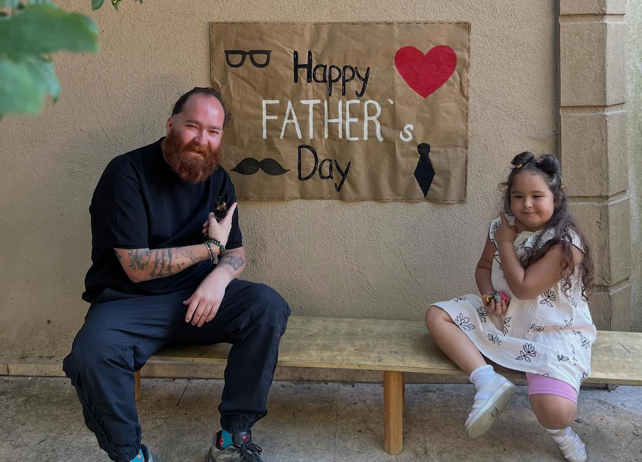 Eren Kasikci sits with his daughter Maya beside a handmade Father's Day sign in a photo shared on June 21, 2026. (Photo via Instagram/@kizilsakalinmutfag)