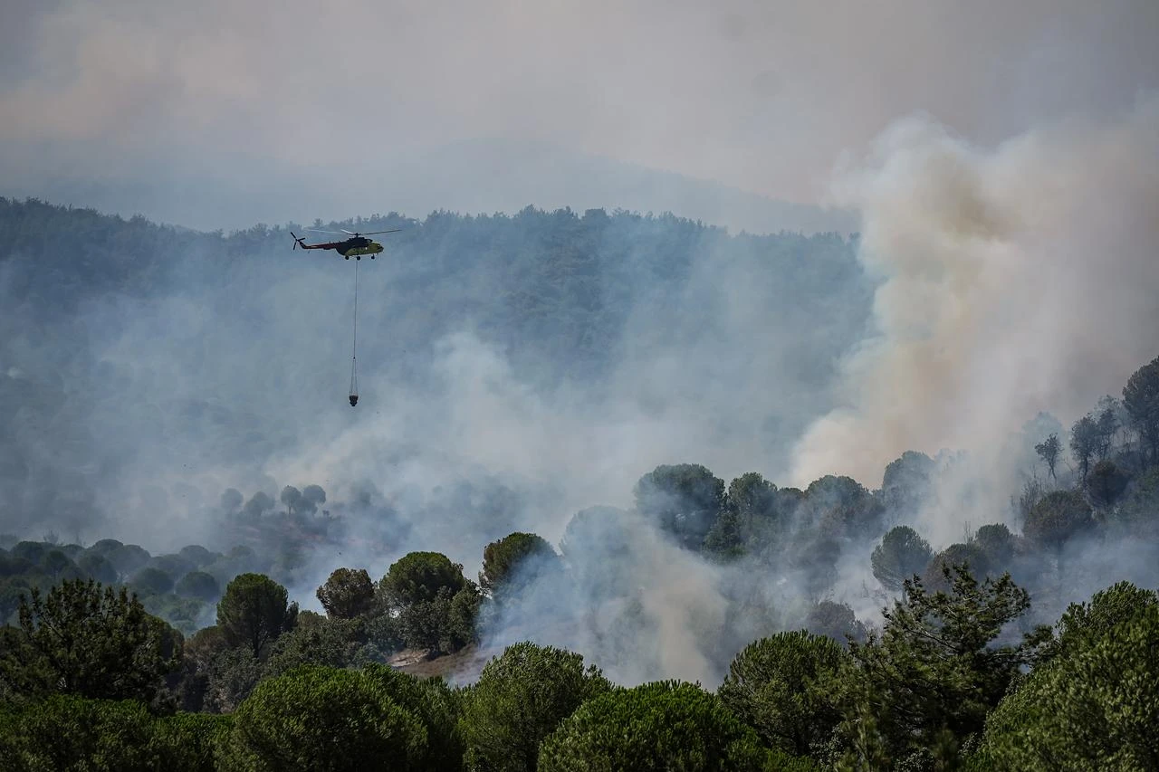 A firefighting helicopter drops water over a forest fire in the Gomec district of Balikesir as aerial and ground crews continue efforts to contain the blaze for a second day, on July 30, 2026 in Balikesir, Türkiye. (AA Photo)