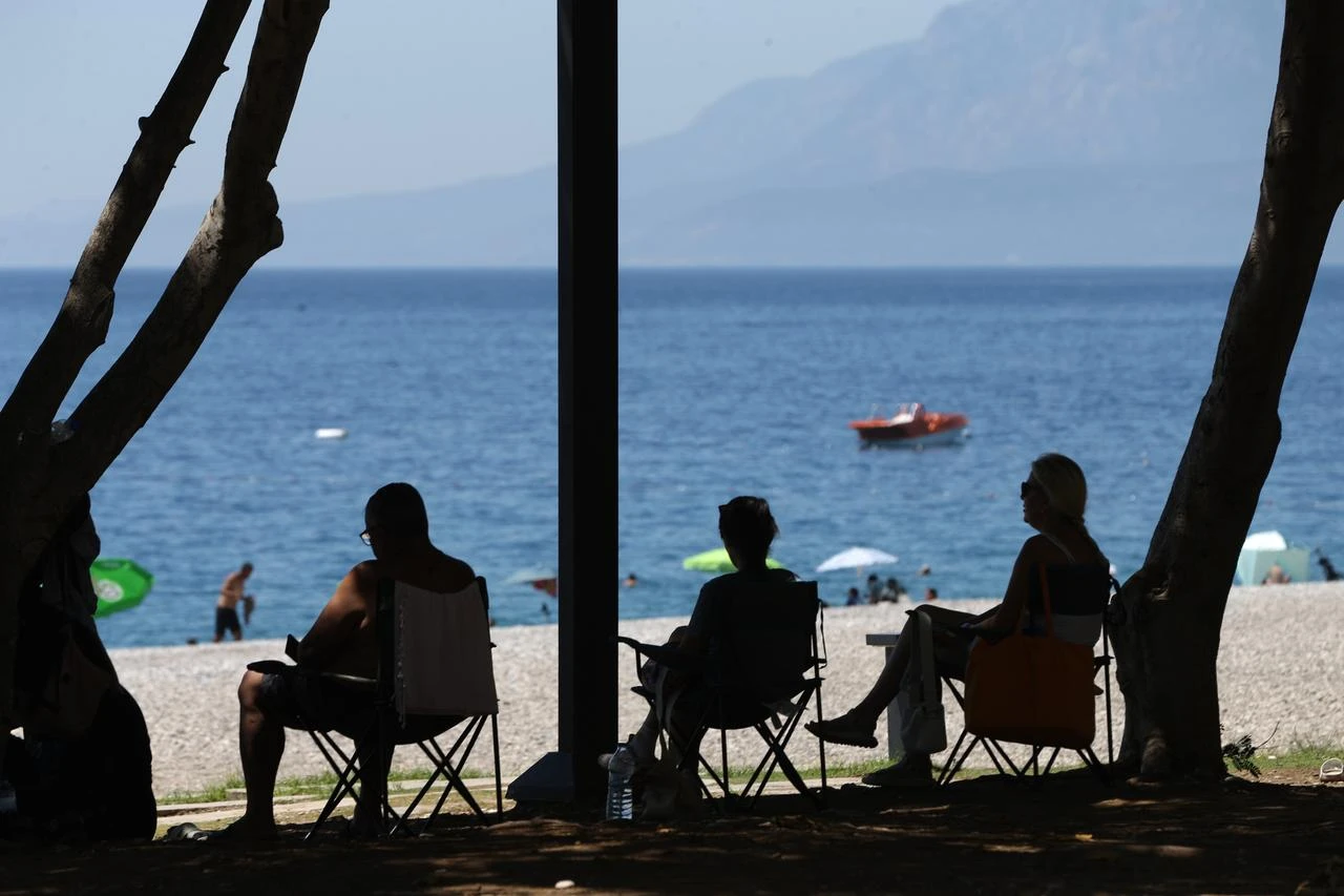 People sit in the shade near a beach as hot weather draws crowds to the coast in Antalya, Türkiye, June 30, 2026. (AA Photo)