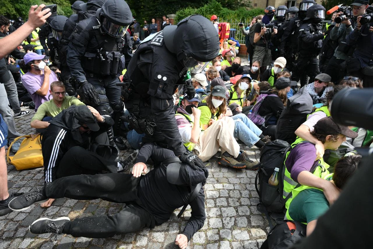 Policemen touch demonstrators sitting on a street near the Gothaer Square in Erfurt to block a way to the Messe Erfurt fairground in Erfurt, eastern Germany on July 4, 2026. (AFP Photo)
