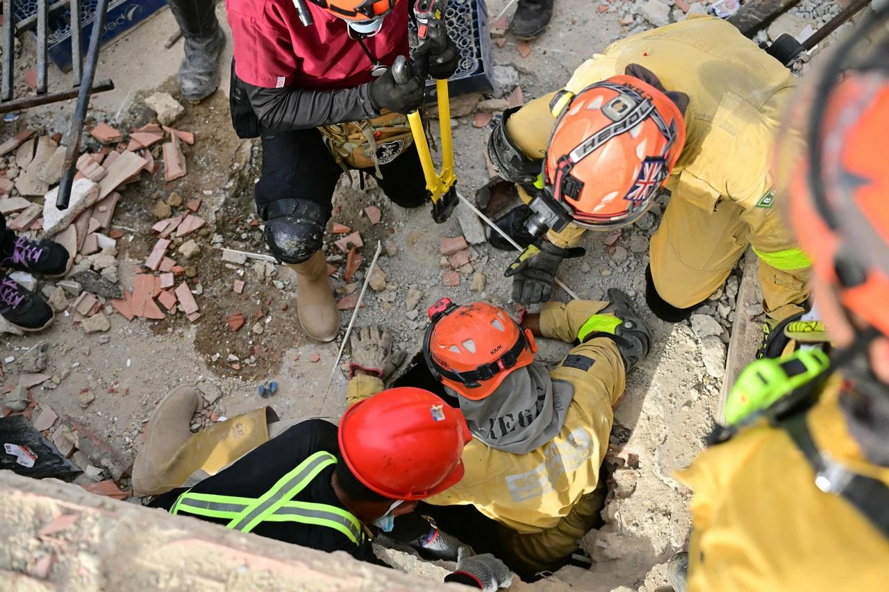 A Brazilian rescuer emerges from a hole as fellow rescue workers assist during search operations at the site of a collapsed building in La Guaira, Venezuela, July 4, 2026. (AFP Photo)