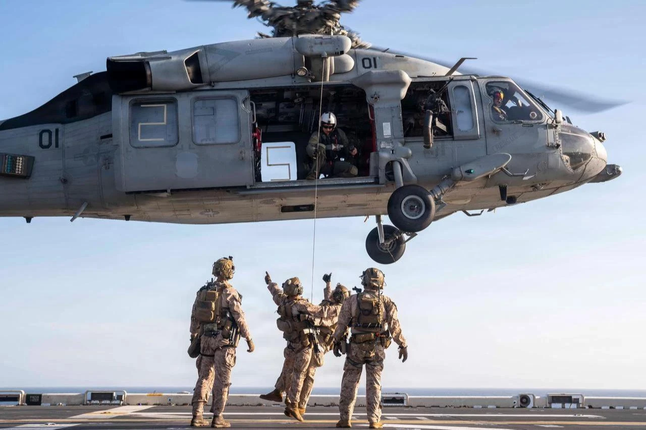 U.S. Sailors and Marines conduct live-hoist training with an MH-60S Sea Hawk helicopter on the flight deck of the America-class amphibious assault ship USS Tripoli (LHA 7), April 15, 2026. (Photo via U.S. Navy)