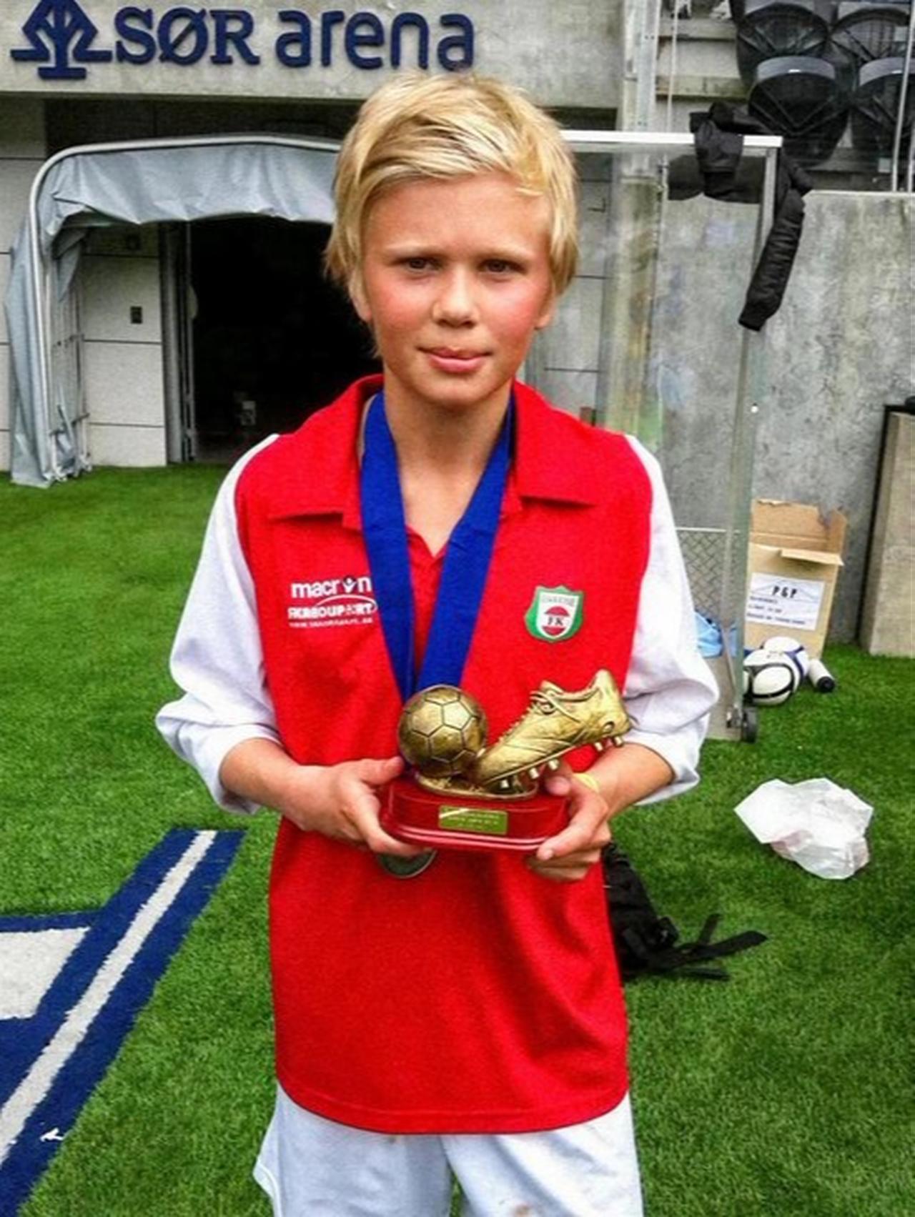 Photo of Erling Haaland as a pre-teen holding trophe in football pitch. (Photo via X/@MotivacionesF)