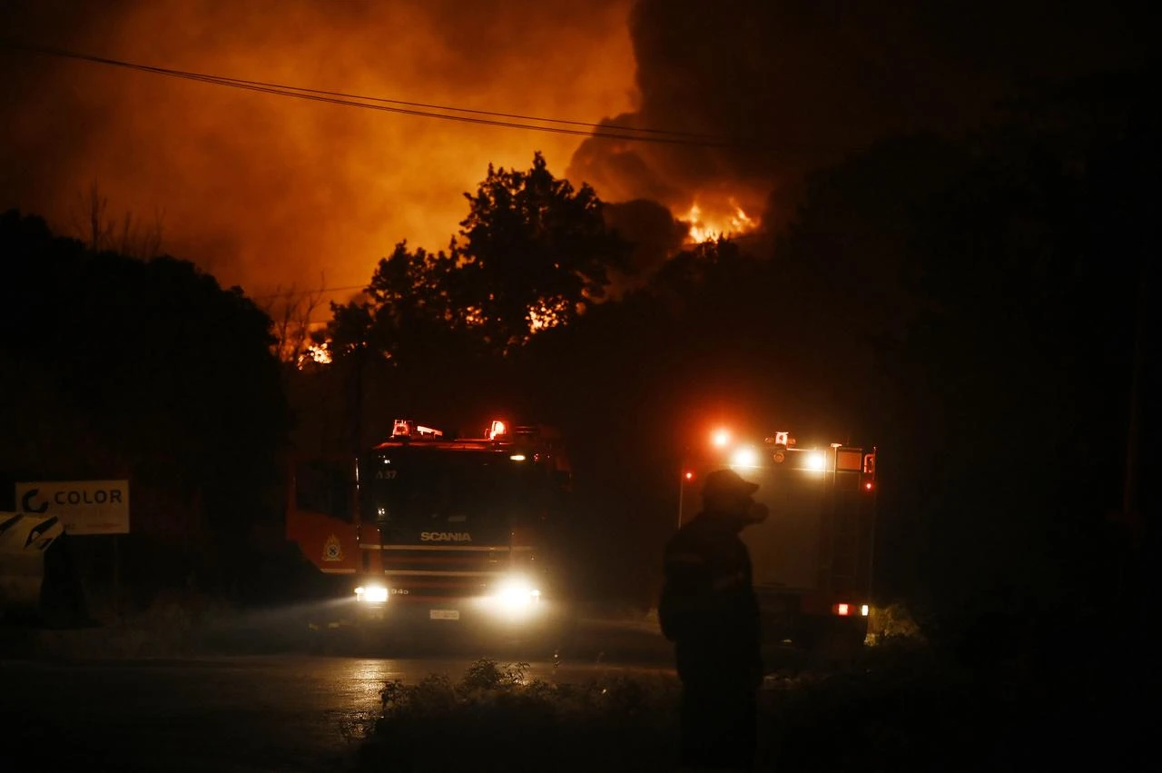 Flames light up the sky as wildfire threatens nearby homes, while emergency personnel respond on the ground in Oreokastro, a suburb north of Thessaloniki, Greece, on July 5, 2026. (AFP Photo)