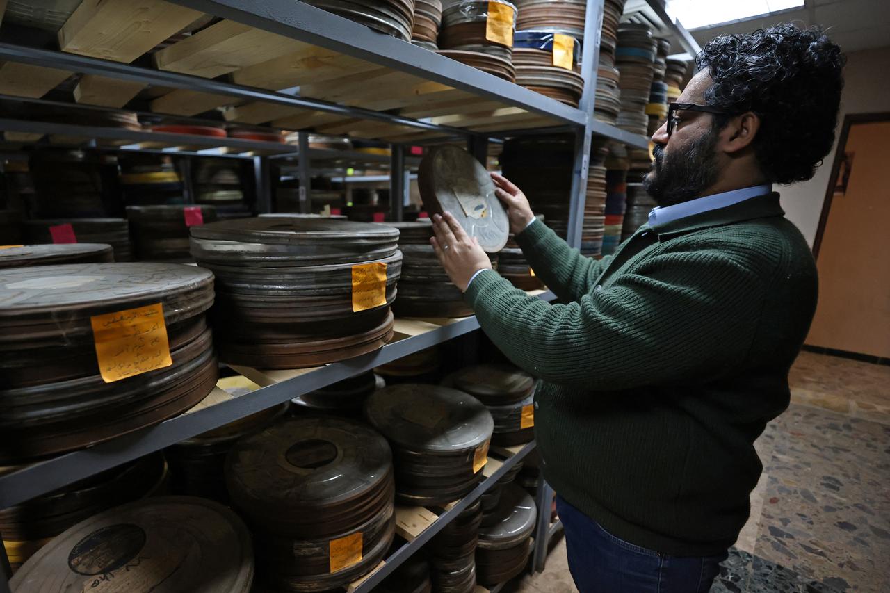 Wareth Kwaish, a filmmaker, inspects a film reel at the National Centre for Archives and Iraqi Memory in Baghdad on February 5, 2026. (AFP Photo)