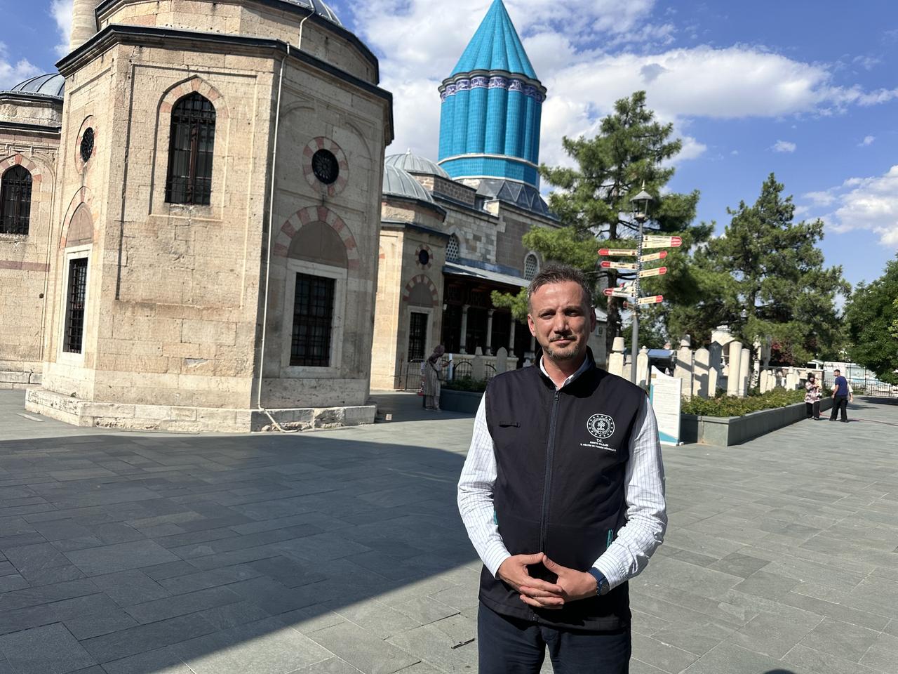 Konya Culture and Tourism Director Fikret Fidan stands inside the Mevlana Museum complex in Konya, with the museum's iconic turquoise dome in the background. (AA Photo)