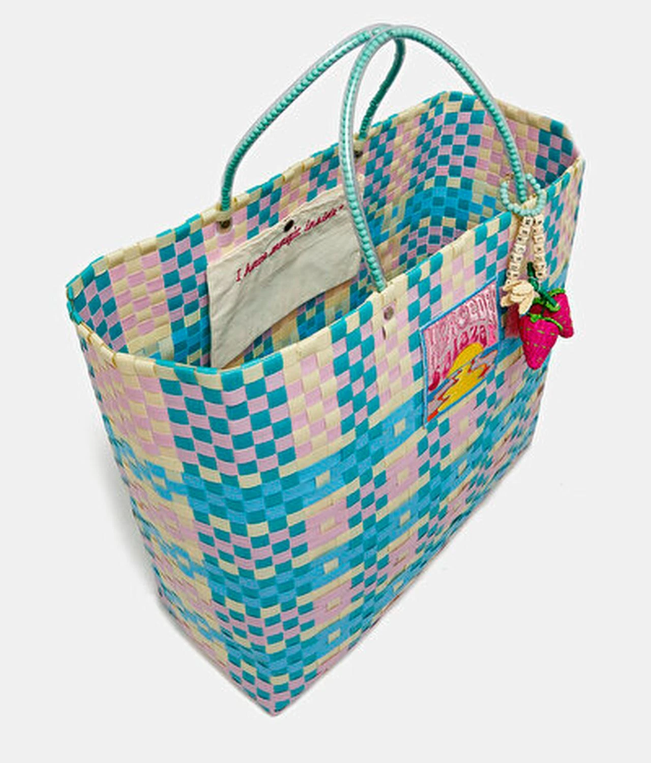 An angled view of a Mercedes Salazar tote reveals its open interior, structured woven body and decorative exterior charms. (Image via Mercedes Salazar)