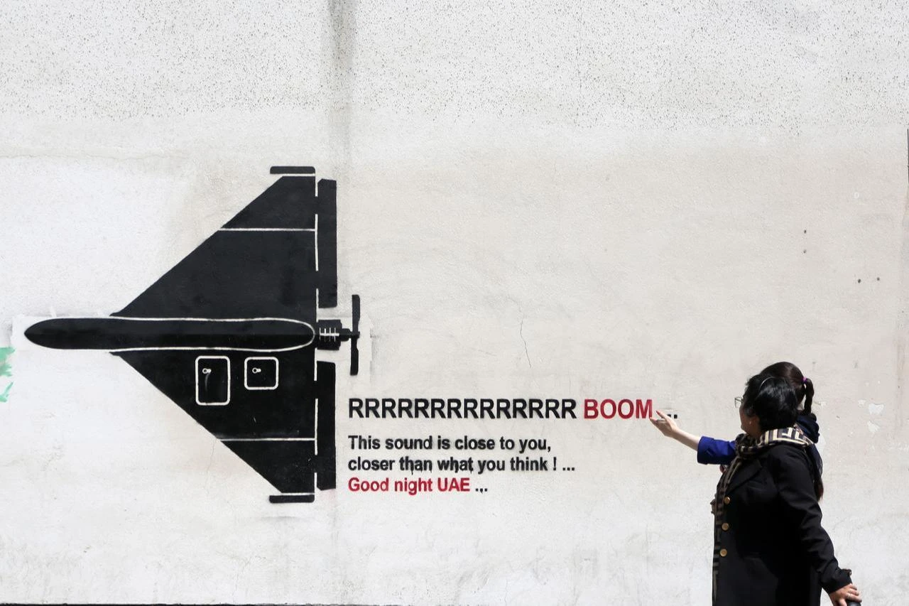 Citizens walk past war-themed graffiti and murals painted on walls along the streets and avenues of Tehran, the capital, on July 22, 2026, in Tehran, Iran. (AA Photo)