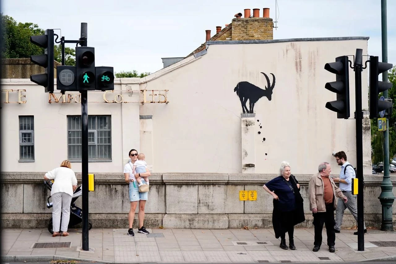 People standing in front of Banksy's new goat mural in south-west London, August 6, 2024. (PA Photo)
