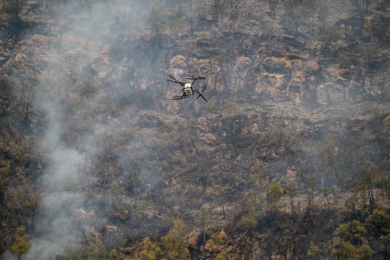 A drone flies over a scorched hillside during efforts to monitor a wildfire in Indonesia, Aug. 6, 2026. (AFP Photo)