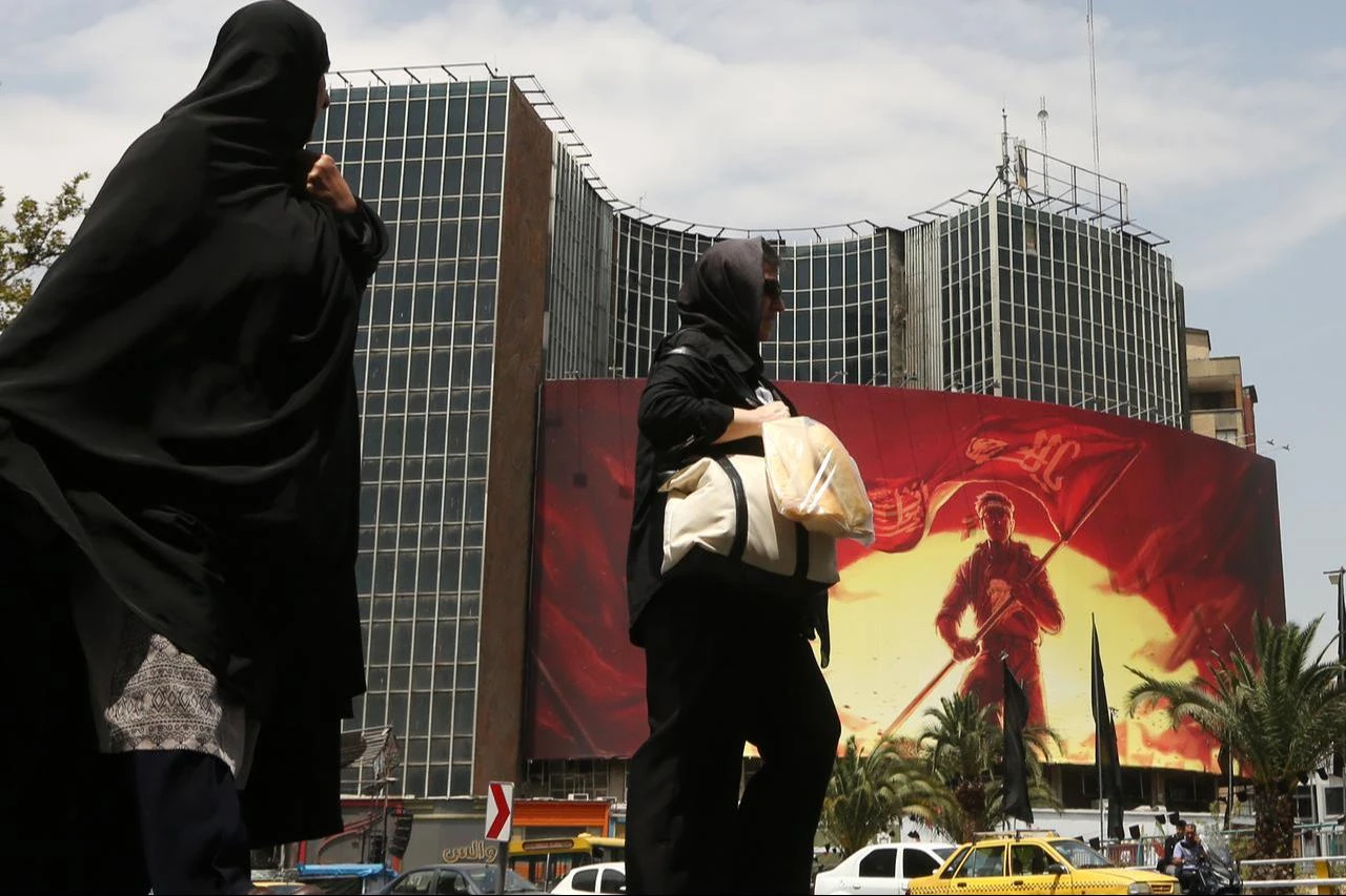 People walk in front of a giant banner as daily life continues amid ongoing tensions between the United States in Tehran, Iran, August 6, 2026. (AA Photo)