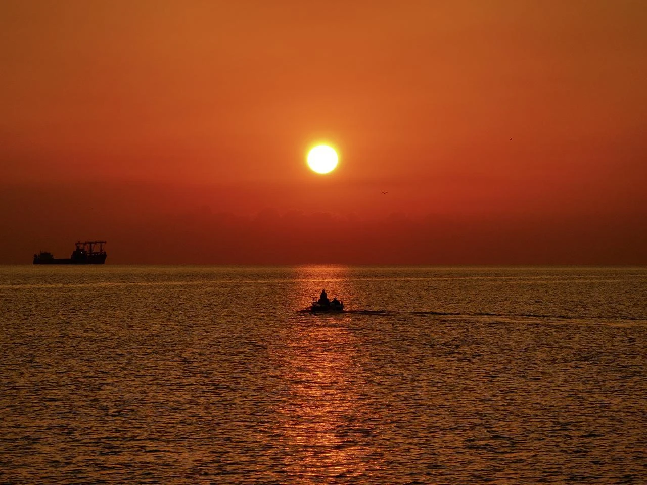 A person travels by boat on the Black Sea as the sky glows red during sunrise near Bati Park in the Ilkadim district of Samsun, Türkiye, August 9, 2026. (AA Photo)