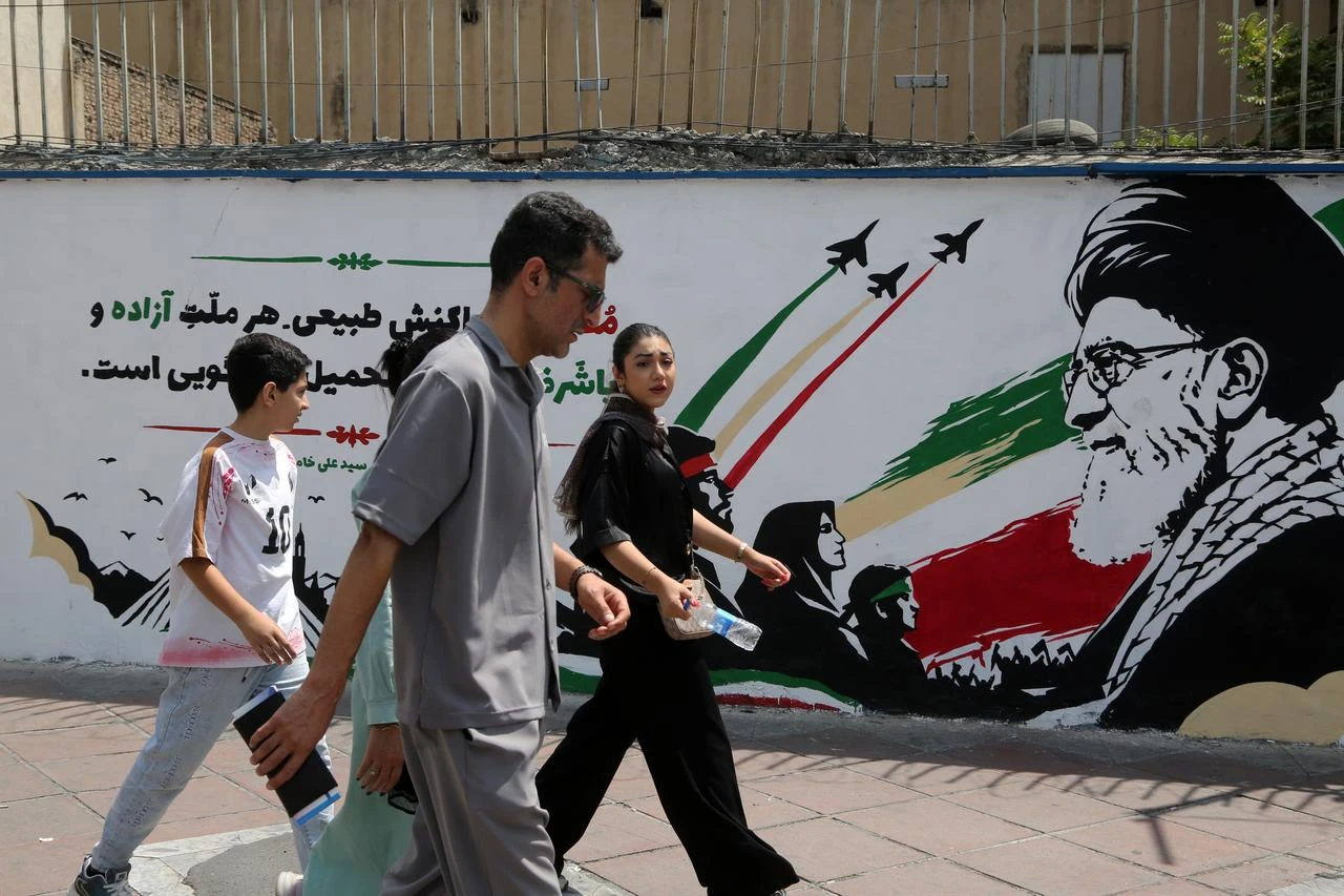People walk in front of a wall mural as daily life continues amid ongoing tensions between the United States in Tehran, Iran, on August 6, 2026. (AA Photo)