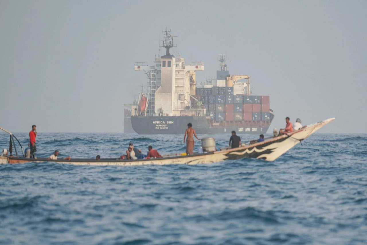 People sail their boat past container ships anchoring near the Strait of Bab al-Mandeb off Yemen's coast in the Gulf of Aden on August 6, 2026. (AFP Photo)