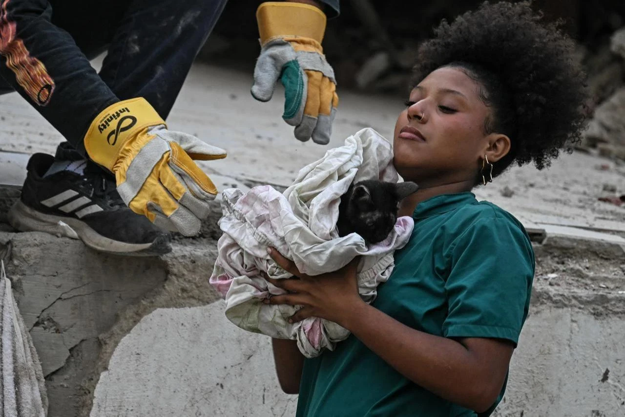 Volunteer rescuer holds a cat after pulling it out from under the rubble of a building damaged by the June 24 earthquakes, in Venezuela, on July 18, 2026. (AFP Photo)