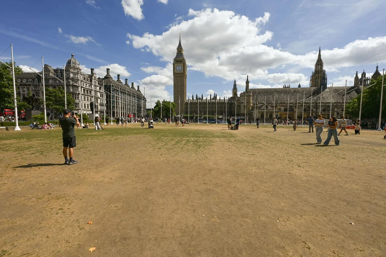 Visitors cross parched grass near the Houses of Parliament as drought conditions affect Parliament Square in London, U.K., Aug. 10, 2026. (AA Photo)