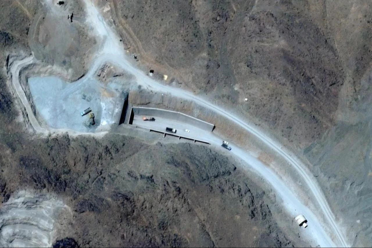 This handout satellite image shows vehicles at the western entrance of the Pickaxe Mountain tunnel complex adjacent to the Natanz Nuclear Facility near Natanz, Isfahan province, central Iran, June 21, 2026. (Photo by Satellite image ©2026 Vantor/AFP)