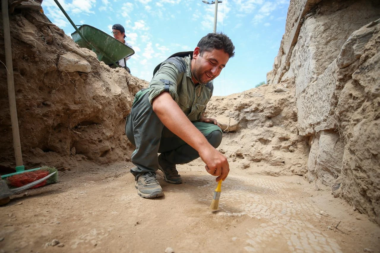An archaeologist carefully cleans an ancient floor uncovered during excavations at Nysa's 1,600-year-old Late Roman bathhouse in Aydin, western Türkiye. (AA Photo)
