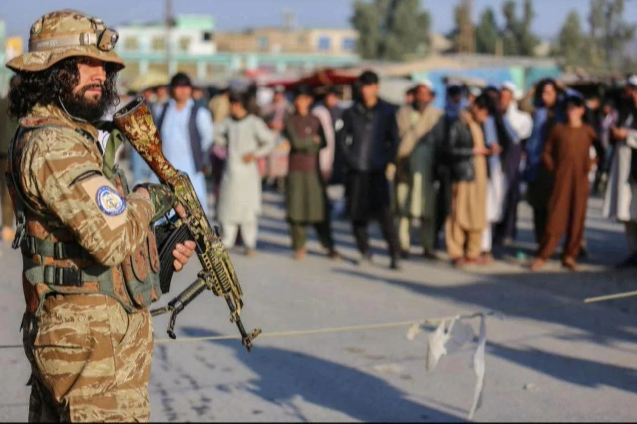 A Taliban security personnel stand guard as Afghan people wait to cross into Pakistan, near the closed Torkham gate at the Torkham border crossing between Afghanistan and Pakistan, in Nangarhar province, February 23, 2023. (AFP Photo)