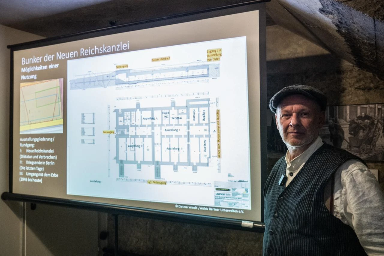 Chairman of the "Berliner Unterwelten" association poses next to archive photos of the underground bunker (L) of the New Reich Chancellery during its construction in the late 1930's. (AFP Photo)