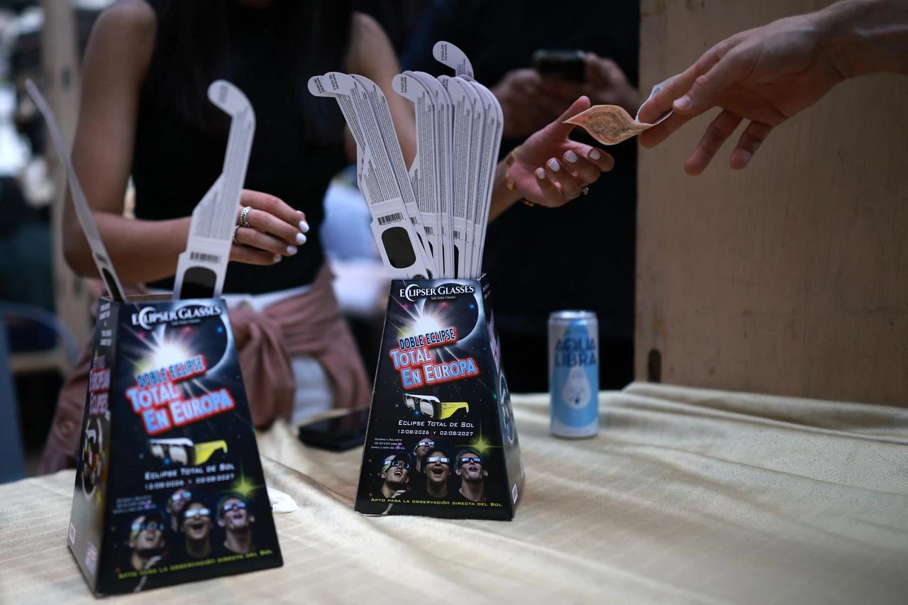 Cash is handed over to purchase solar eclipse glasses at an outlet within Old Spitalfields Market in east London on August 11, 2026, ahead of the total eclipse of the sun expected in parts of Europe. (AFP Photo)