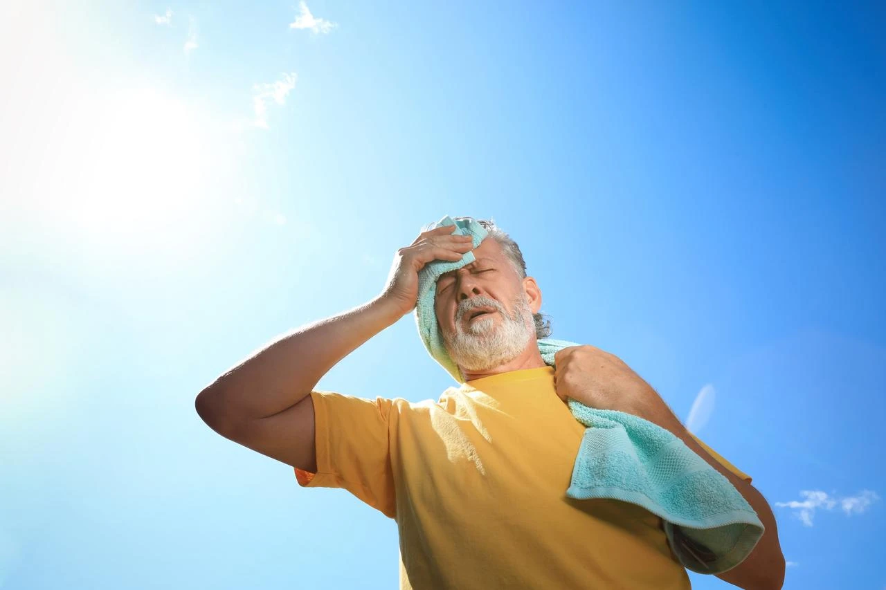Senior man with a towel suffering from heat stroke outdoors. (Photo via Adobe Stock)