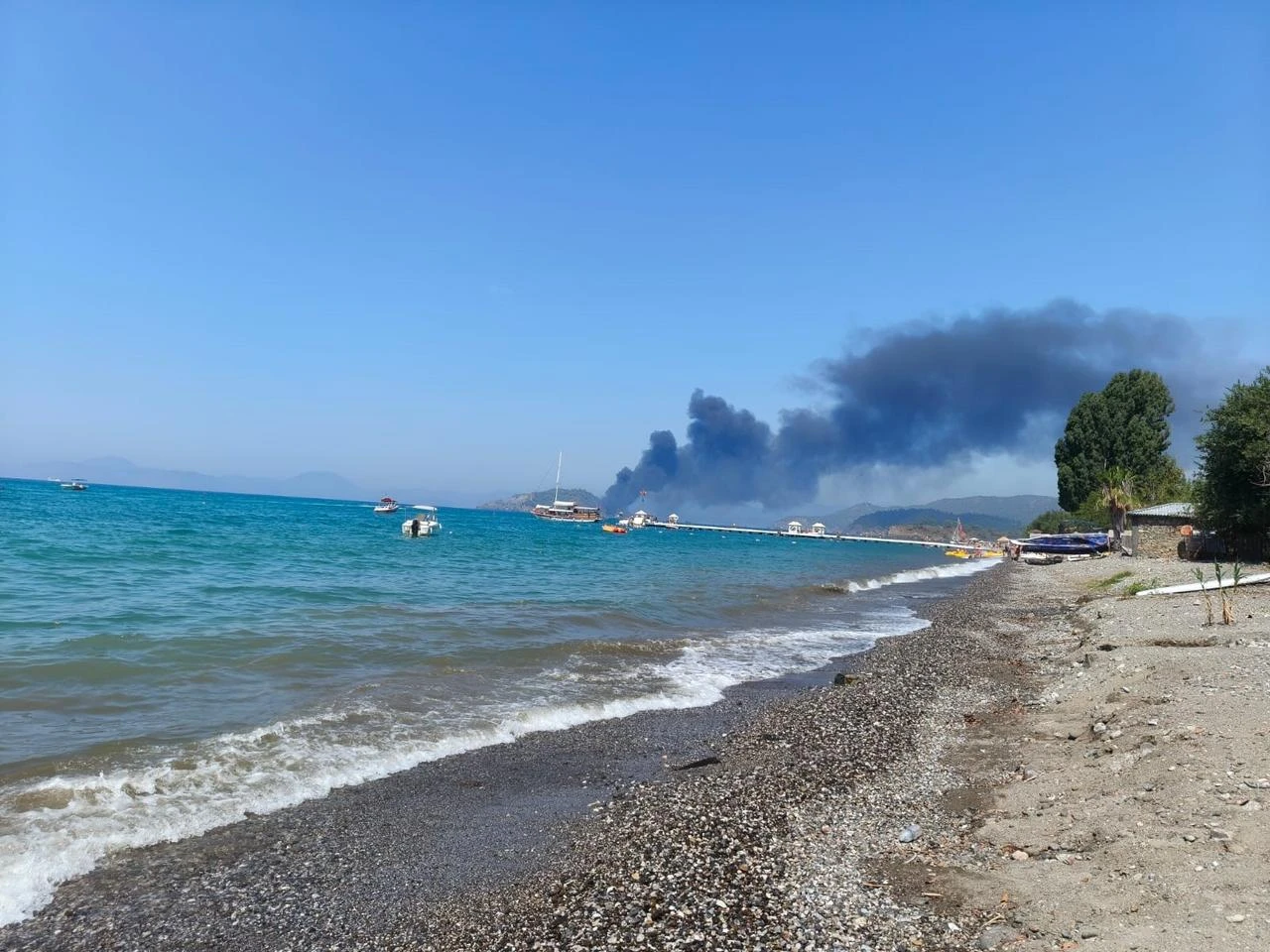 A plume of black smoke rises over the sea after a tour boat caught fire off Fethiye in Mugla, southwestern Türkiye, Aug. 13, 2026. (IHA Photo)
