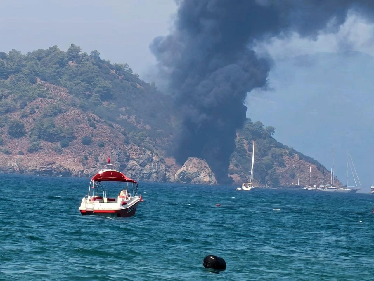 A plume of black smoke rises over the sea after a tour boat caught fire off Fethiye in Mugla, southwestern Türkiye, Aug. 13, 2026. (IHA Photo)