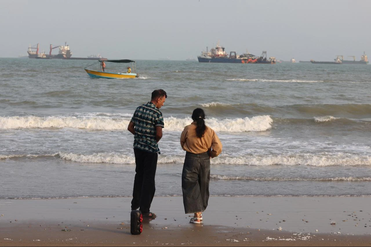 Iranians enjoy the seaside as vessels are seen in the Strait of Hormuz off Bandar Abbas, in southern Iran on August 10, 2026. (AFP Photo)