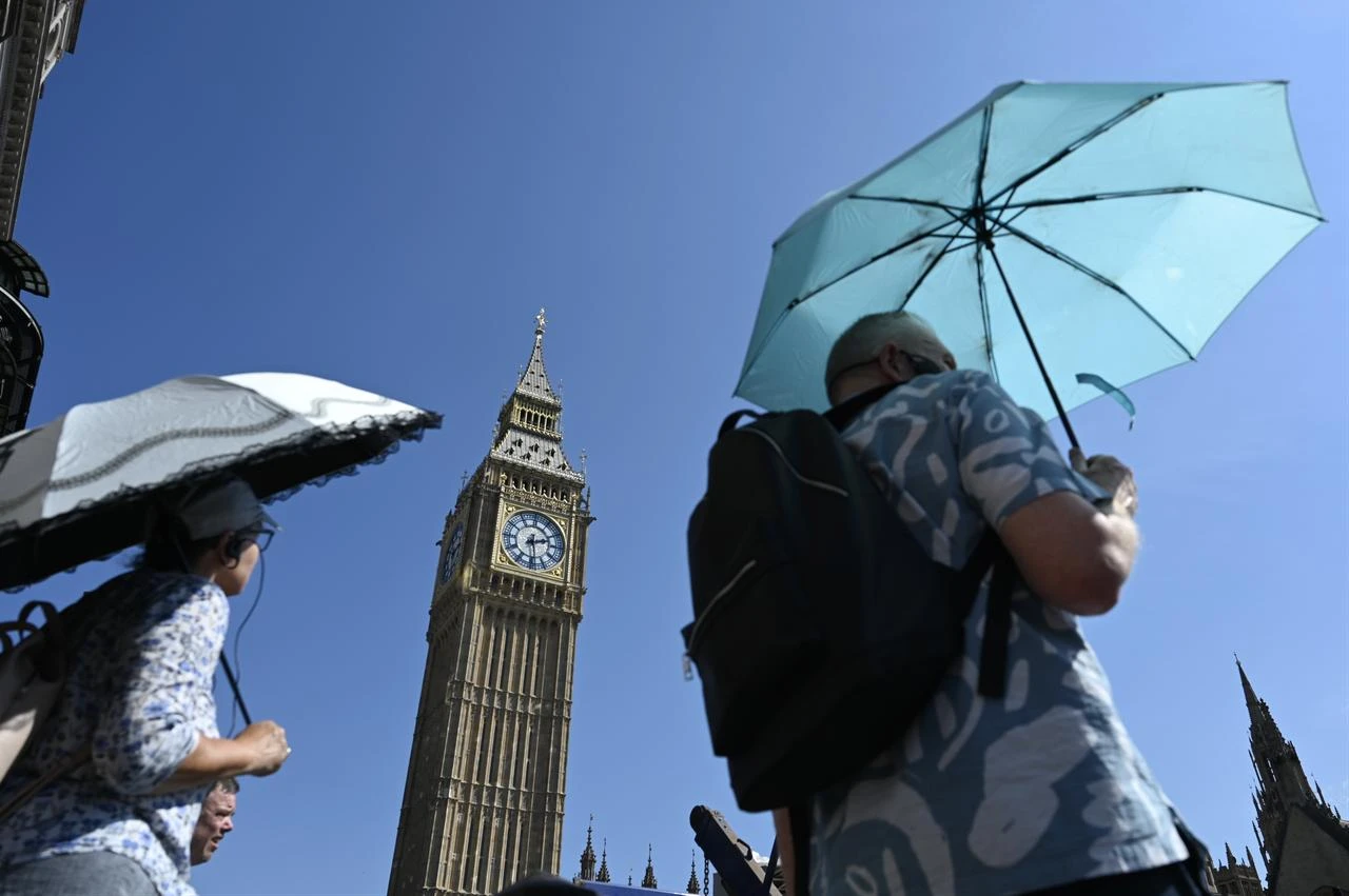 People use umbrellas for shade near Elizabeth Tower as extreme heat hits London, U.K., Aug. 13, 2026. (AA Photo)